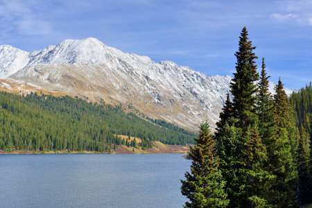 bright landscape view of the snow covered mountains and trees during foliage season in Coloradoの写真素材