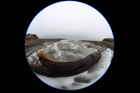 River flows into the sea. Circular fisheye landscape. Dark winter day