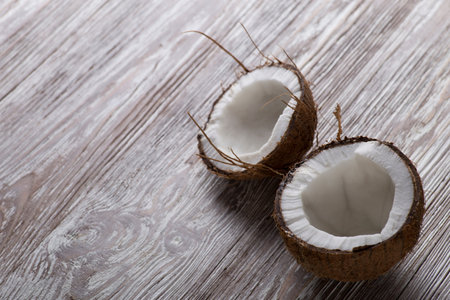Two halves of coconut on a brown wooden board