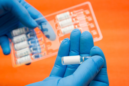 Ampoules with a medicine for a vaccine against diseases, flu in the hands of a medic with gloves -...