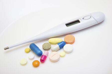 Electronic thermometer with tablets and capsules on a white background - protection against influenza during quarantine, coronavirus, covid19の写真素材