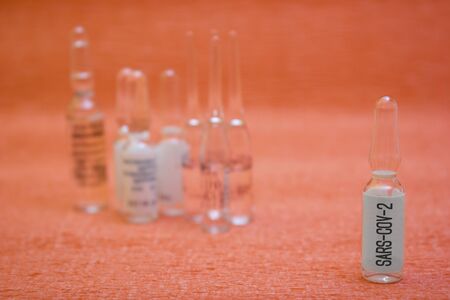 Ampoules with a medicine for a vaccine for diseases, flu - search for a vaccine, treatment of influenza, coronavirus, covid19, lettering sars-cov-2の写真素材