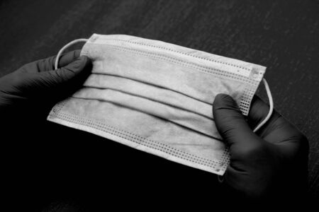Hands in medical gloves hold a protective mask - protection against influenza during quarantine, coronavirus, covid19, black and whiteの写真素材