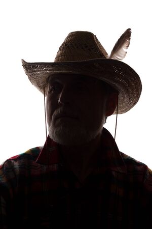Portrait of a old man, in a cowboy hat with feather, with beard, front view - dark isolated silhouetteの写真素材