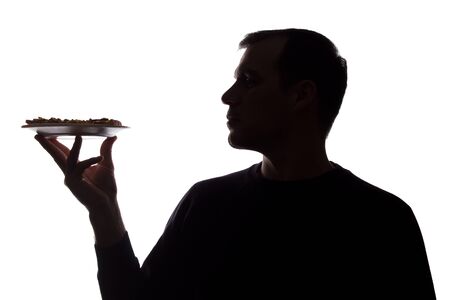 Portrait of a young man with a pizza on a dish in hand, unshaven, side view - dark isolated silhouetteの写真素材
