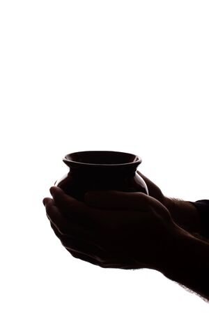 The hand of a young man holds a ceramic pot - silhouette, conceptの写真素材