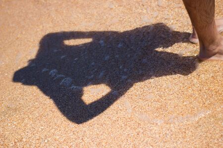 Sea water wave shadow from a man in a hat on sand background textureの写真素材