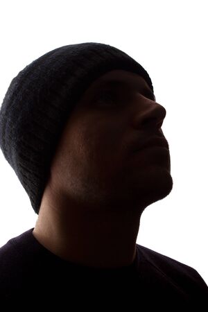 Portrait of a young man, unshaven, side view in cap - dark isolated silhouetteの写真素材