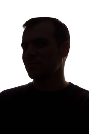 Portrait of a young man, unshaven, side view - dark isolated silhouetteの写真素材