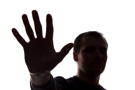 The hand of a young man covers his face, protest - silhouette, concept without commentの写真素材