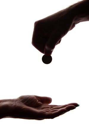 Young man's hand with a coin gives alms - silhouette, help conceptの写真素材
