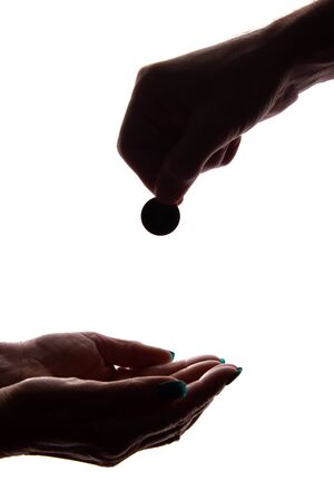 Young man's hand with a coin gives alms - silhouette, help conceptの写真素材