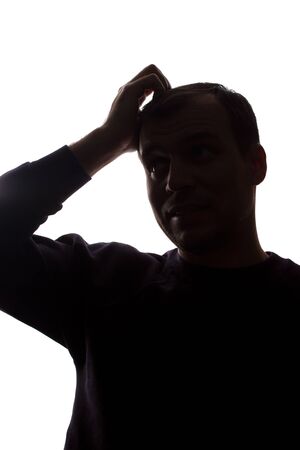 Portrait of a young man, unshaven, front view - dark isolated silhouetteの写真素材
