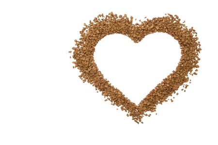 Dry instant coffee granules in the shape of a heart - brown texture, on a white backgroundの写真素材