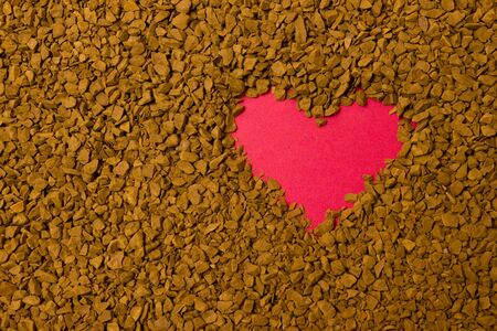 Dry instant coffee granules in the shape of a heart - brown texture, drinkの写真素材