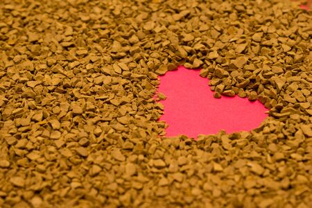 Dry instant coffee granules in the shape of a heart - brown texture, drinkの写真素材