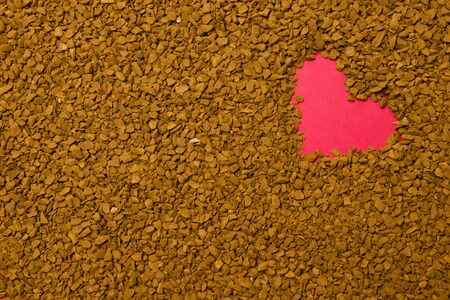 Dry instant coffee granules in the shape of a heart - brown texture, drinkの写真素材