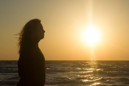 Silhouette of a girl on the beach at sunrise - with flowing hairの写真素材