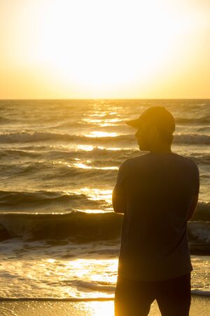 Portrait of a young man in cap on the beach - at sunriseの写真素材