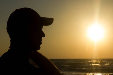 Portrait of a young man in cap on the beach - at sunriseの写真素材