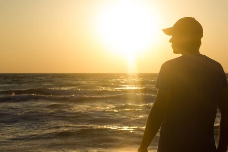 Portrait of a young man in cap on the beach - at sunriseの写真素材