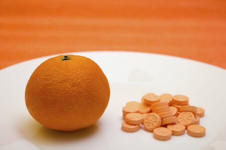 Tablets and orange on a white background - vitamin, protection against influenza during quarantine, coronavirus, covid19の写真素材