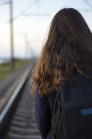 Girl walks on railway rails in a coat - travel, depression, lifestyleの写真素材