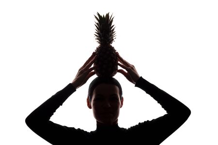 Pineapple in a woman's hands above the head - silhouette on white backgroundの写真素材