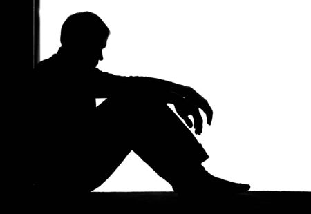 Young man with grief dropped his arms - dark silhouetteの写真素材