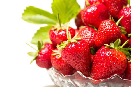 Ripe tasty strawberries with green leaves in a glass vase on a white backgroundの写真素材