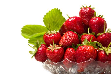 Ripe tasty strawberries with green leaves in a glass vase on a white backgroundの写真素材