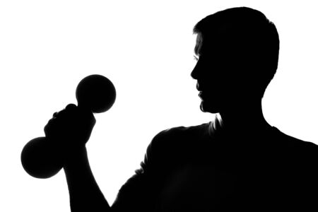Young man with dumbbells in hand - silhouetteの写真素材