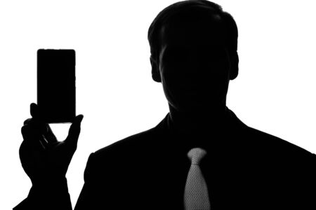 Portrait young business man in suit, tie with smartphone, tablet in hand - silhouetteの写真素材