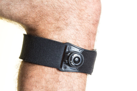 Bandage for the knee with pressure regulator on the male leg - isolate on a white background