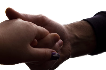 Man gently holding his beloved by the hand - closeup silhouette love concept