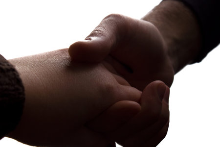 Man gently holding his beloved by the hand - closeup silhouette love concept
