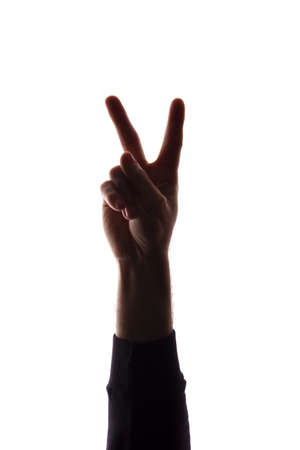 The hand of a young man with his fingers apart, number the two - silhouette, concept abstractionの写真素材