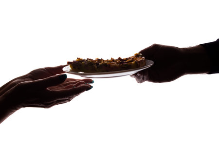 Young man gives a pizza on dish to an elderly woman in her hand - silhouette, help concept