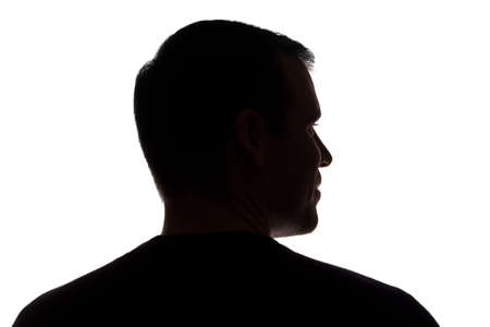 Portrait of a young man, unshaven, back view - dark isolated silhouetteの写真素材