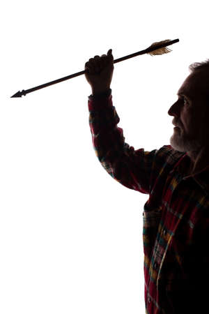 Portrait of a old man, unshaven, with native american arrow in hand with beard, side view - dark isolated silhouette - dark isolated silhouetteの写真素材