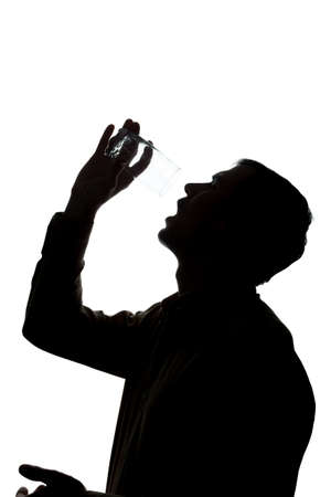 Young man drinking a glass of sparkling water, no water - silhouetteの写真素材
