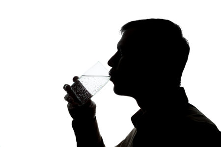 Young man drinking a glass of sparkling water - silhouette