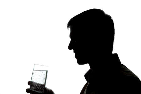 Young man drinking a glass of sparkling water - silhouetteの写真素材