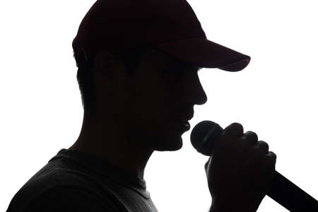 Young man in cap singing into a microphone - silhouetteの写真素材