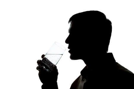 Young man drinking a glass of sparkling water - silhouetteの写真素材