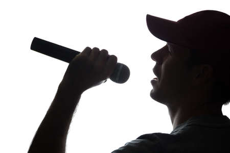 Young man in cap singing into a microphone - silhouetteの写真素材