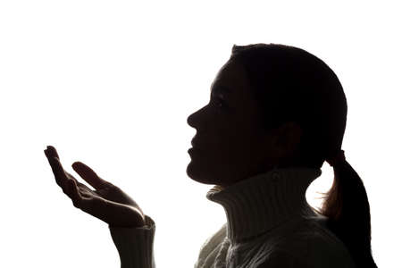 Young woman looking up with hope and request - horizontal silhouette of a side viewの写真素材