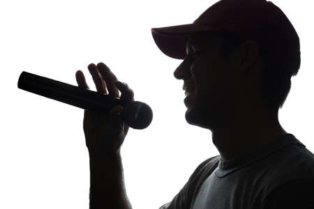 Young man in cap singing into a microphone - silhouetteの写真素材