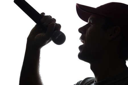 Young man in cap singing into a microphone - silhouetteの写真素材