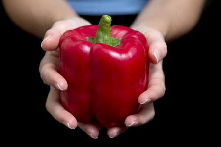 Red pepper on a woman's hand on black background - horizontalの写真素材